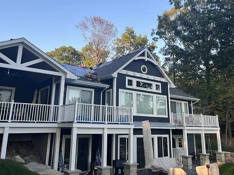Crew installing new shingles on blue home