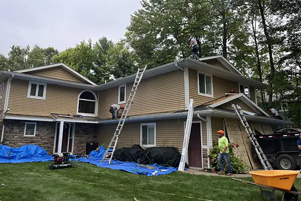 Crew installing new shingles on beige home